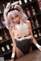 A woman dressed as a bunny sitting at a bar.