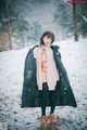 A woman standing in the snow wearing a black coat.