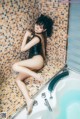 A woman in a black bathing suit sitting in a bathtub.