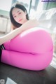 A woman sitting on a pink bean bag chair.