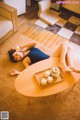 A woman laying on the floor with a tray of tea cups.