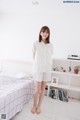 A woman standing in front of a bed in a bedroom.