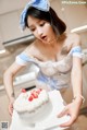 A woman in a maid outfit holding a cake.