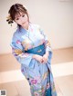 A woman in a blue kimono posing for a picture.