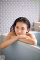 A young woman sitting in a bathtub with her arms crossed.