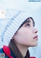 A woman wearing a white knitted hat in the snow.