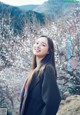 A woman standing in front of a flowering tree.