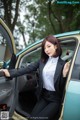 A woman in a business suit sitting in a car.