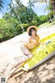 A woman in a yellow bikini sitting on an inflatable raft on the beach.