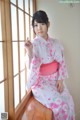 A woman in a pink and white kimono sitting on a window sill.