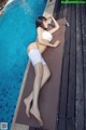 A woman in a white bikini laying on the edge of a pool.