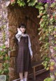 A woman standing in front of a stone wall.