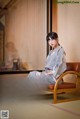 A woman in a kimono sitting on a chair in a room.