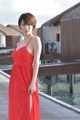 A woman in a red dress standing on a dock.